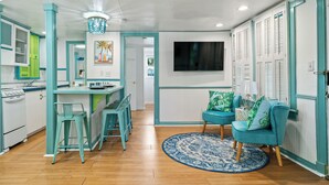 A modern kitchen with teal accents, a dining area with matching chairs, and a cozy seating area with a patterned rug. - Summer Family Fun, Pet Friendly, Walk Downtown, Close to Beach, Fenced Courtyard (Lake Worth Beach)