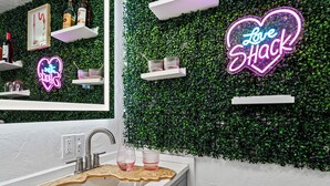 A bathroom with a green wall, a neon sign, and a sink with a decorative mat. - Summer Family Fun, Pet Friendly, Walk Downtown, Close to Beach, Fenced Courtyard (Lake Worth Beach)