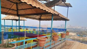 A covered outdoor seating area with blue railings and terracotta planters. - Hotel Star Residence (Dhaka)