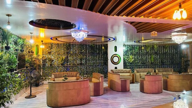 A modern lounge area with circular seating, a decorative ceiling, and a vertical garden wall. - Hotel Star Residence (Dhaka)