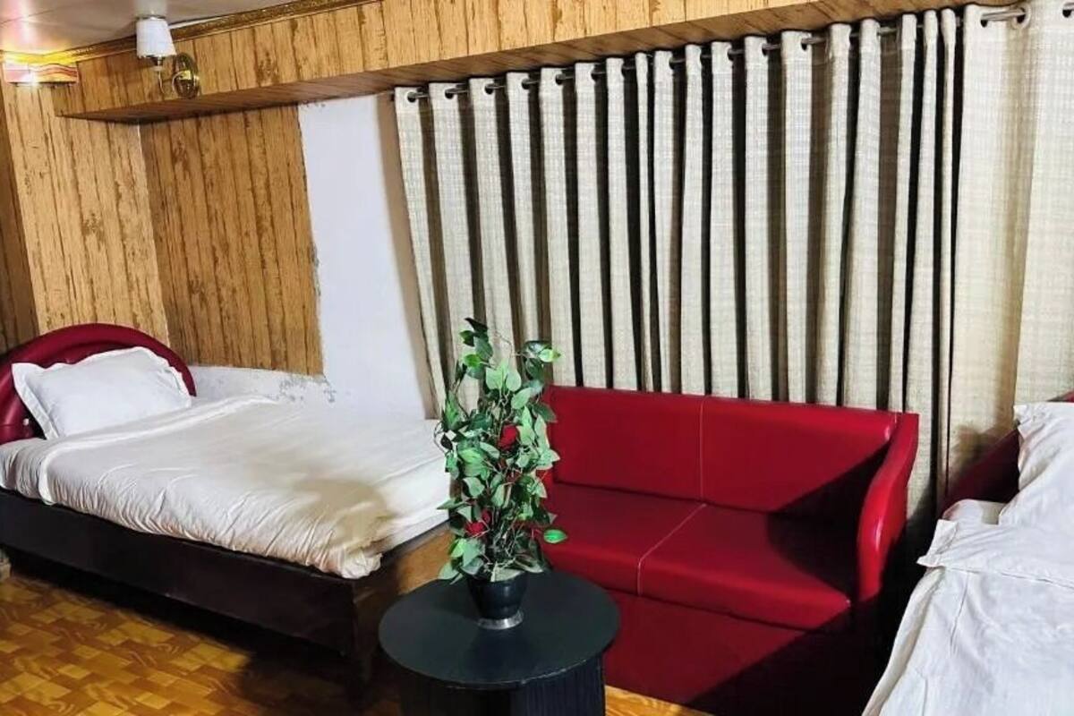 A room with a bed, a red sofa, and a small table with a potted plant.
