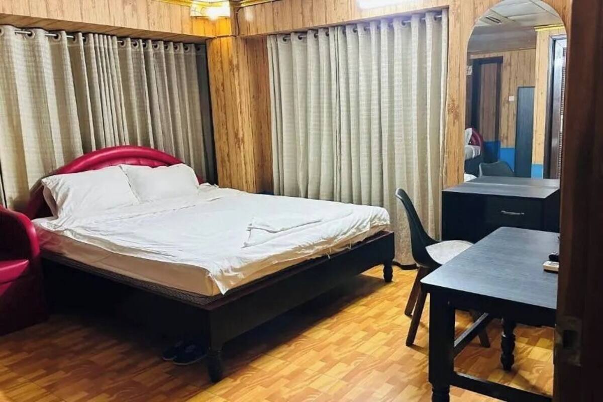 A bedroom with a bed, a desk, and a chair.