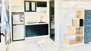 Une cuisine de taille réduite, équipée d’un réfrigérateur, d’un évier et de placards.