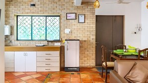 Eine Küche mit Backsteinwand, einem Kühlschrank, einem Essbereich mit Tisch und Stühlen sowie einem braunen Ledersofa.
