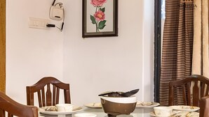 Ein Esstisch mit Glastischplatte, umgeben von Holzstühlen, und ein gerahmtes Blumenbild an der Wand.