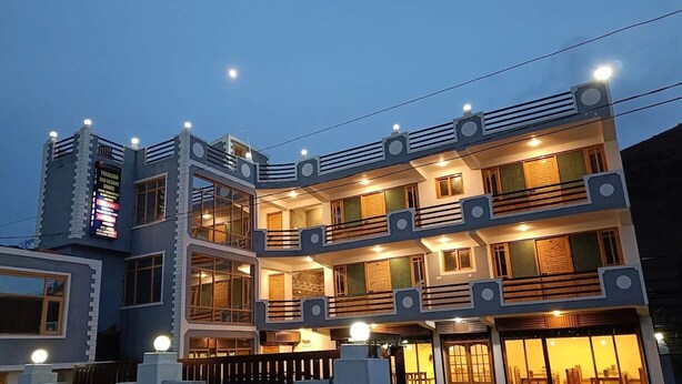 Un edificio de varios pisos con balcones, ventanas amplias y un letrero que indica que es un hotel.
