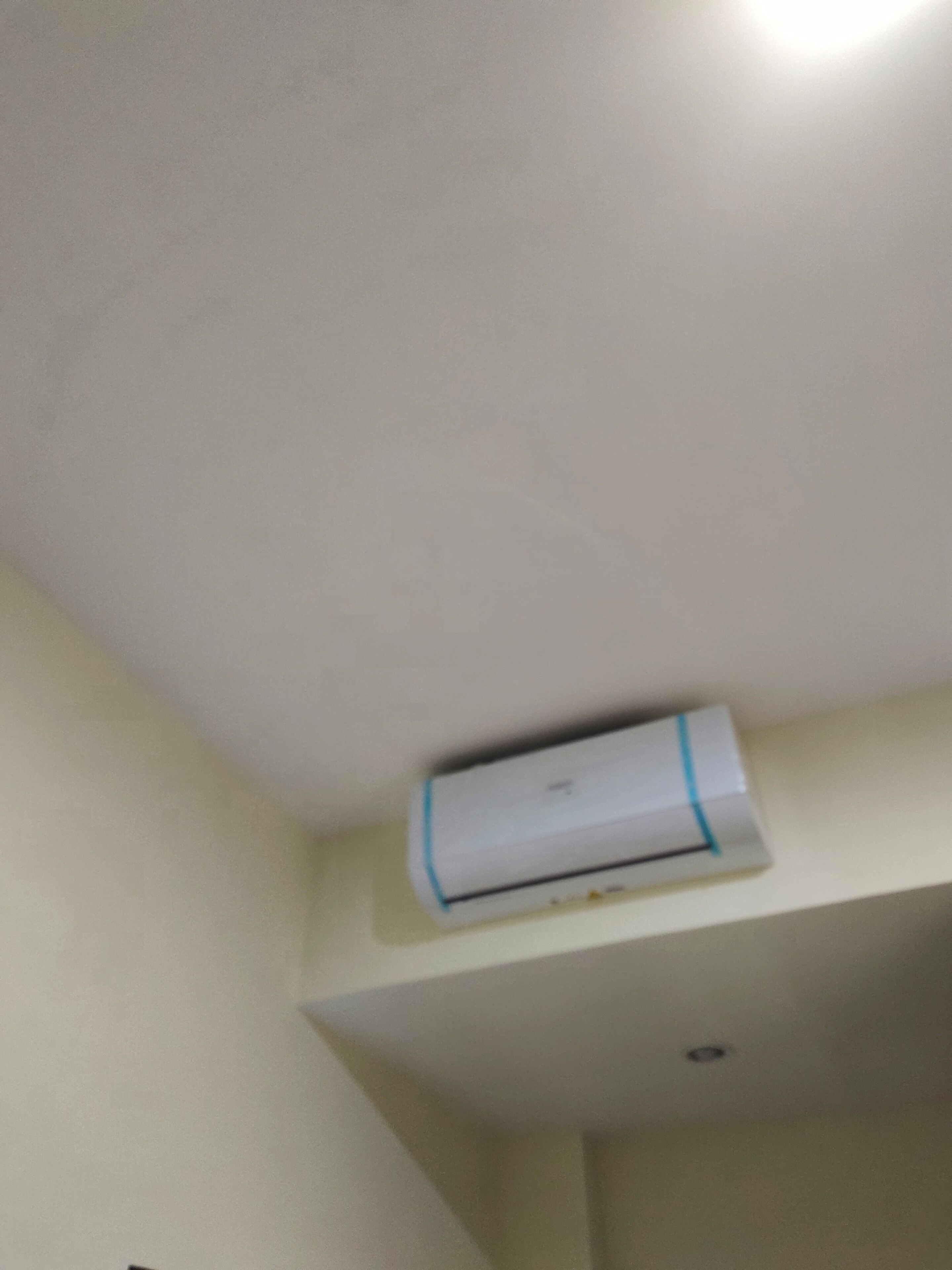A white air conditioning unit mounted on a wall in a room with a white ceiling and walls.