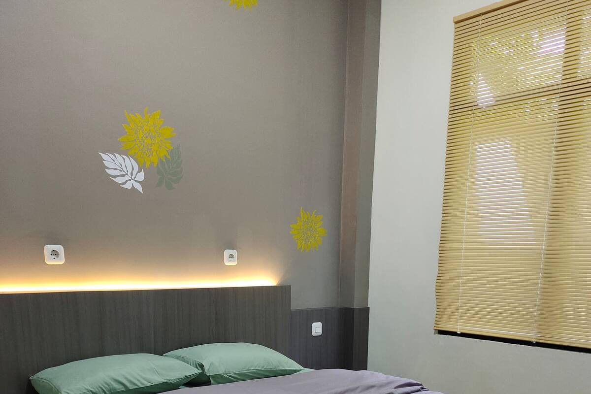 A modern bedroom with a bed, green pillows, and decorative wall art.