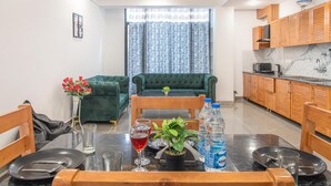Una cocina moderna con armarios de madera, una mesa de comedor para dos personas y un sofá verde al fondo.