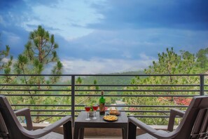 A balcony with a table set for two, featuring a bottle, glasses, and a plate of food. - Mountain Breeze Hill Crest Kasauli (Kasauli)