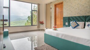 Un dormitorio con un ventanal grande, una cama con cabecera verde y una puerta de madera.