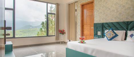 Un dormitorio con un ventanal grande, una cama con cabecera verde y una puerta de madera.