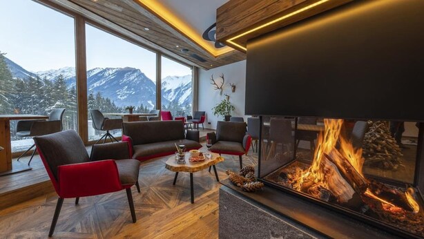 A modern living room with a fireplace, large windows, and a view of snow-capped mountains.