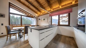 Ett modernt kök med träbjälkar, ett stort fönster och utsikt över bergen.