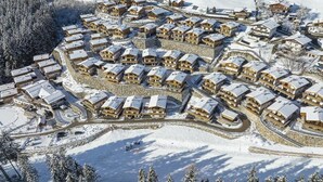 A snow-covered resort with multiple chalet-style buildings arranged in a semi-circular layout.