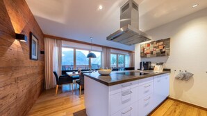 A modern kitchen with a large island, wooden flooring, and a view of mountains.
