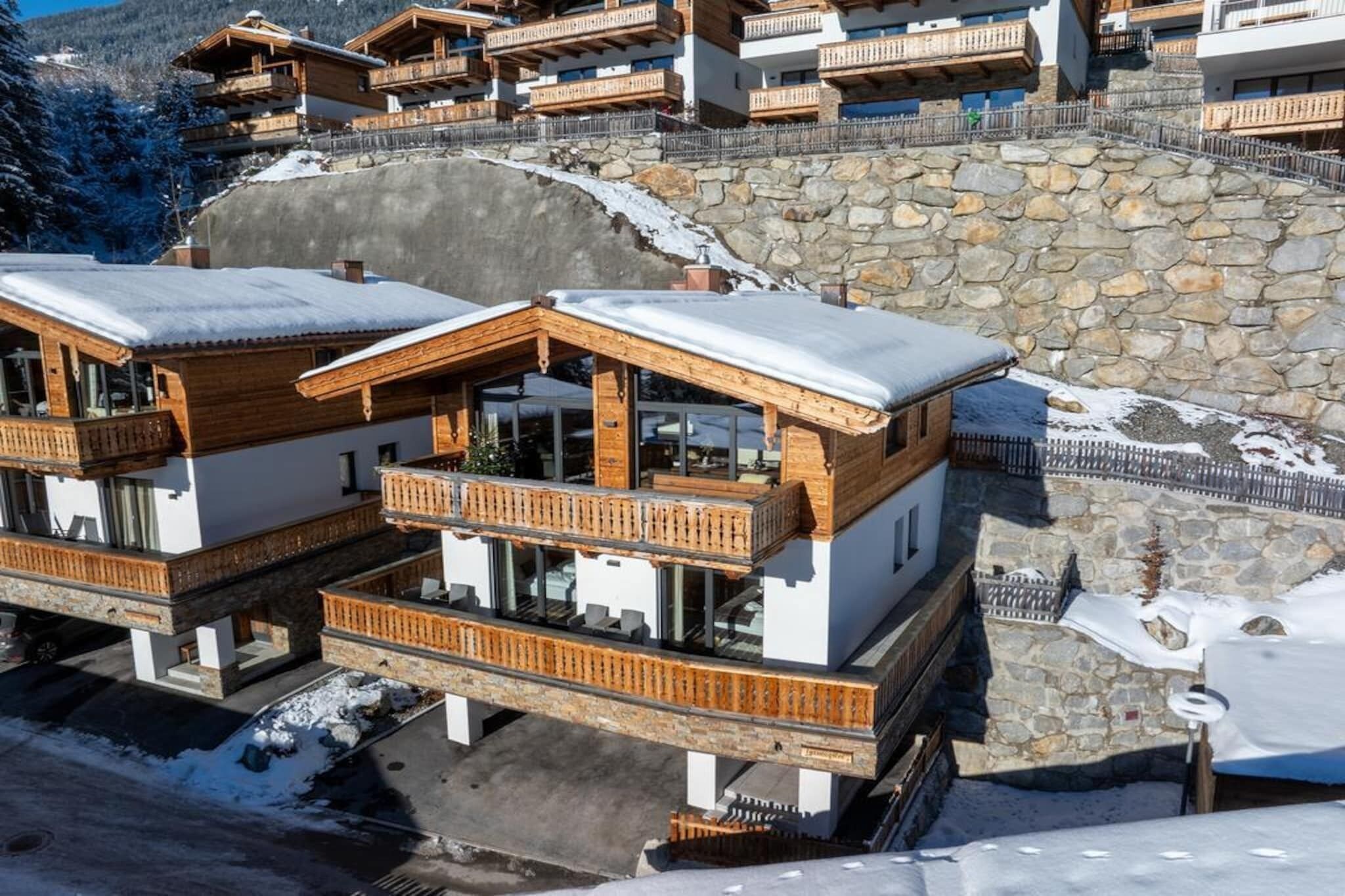Ein modernes Skigebiet mit Holzhütten und Steinmauern, das Balkone und große Fenster bietet.