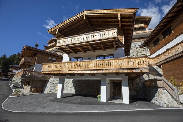 Un immeuble à plusieurs étages doté d’un balcon en bois, de murs en pierre et surplombant un ciel dégagé.