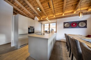 Una cocina moderna con techo de madera, una isla central y un comedor con mesa y sillas.