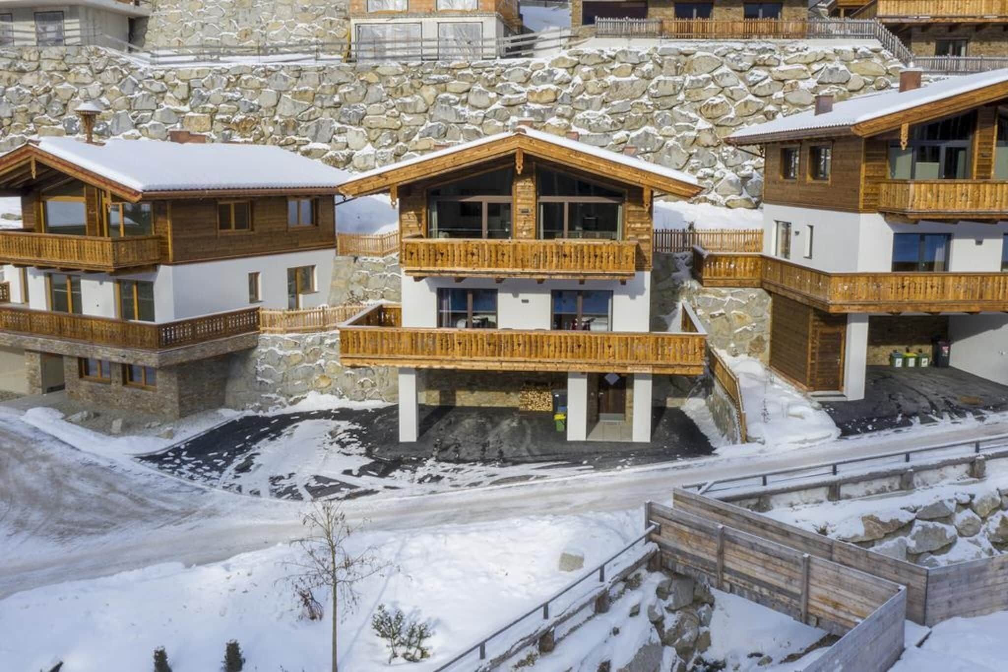 Ein Chalet-Hotel mit Holzbalkonen und Steinwänden, mit mehreren Etagen und einem zentralen Eingang.