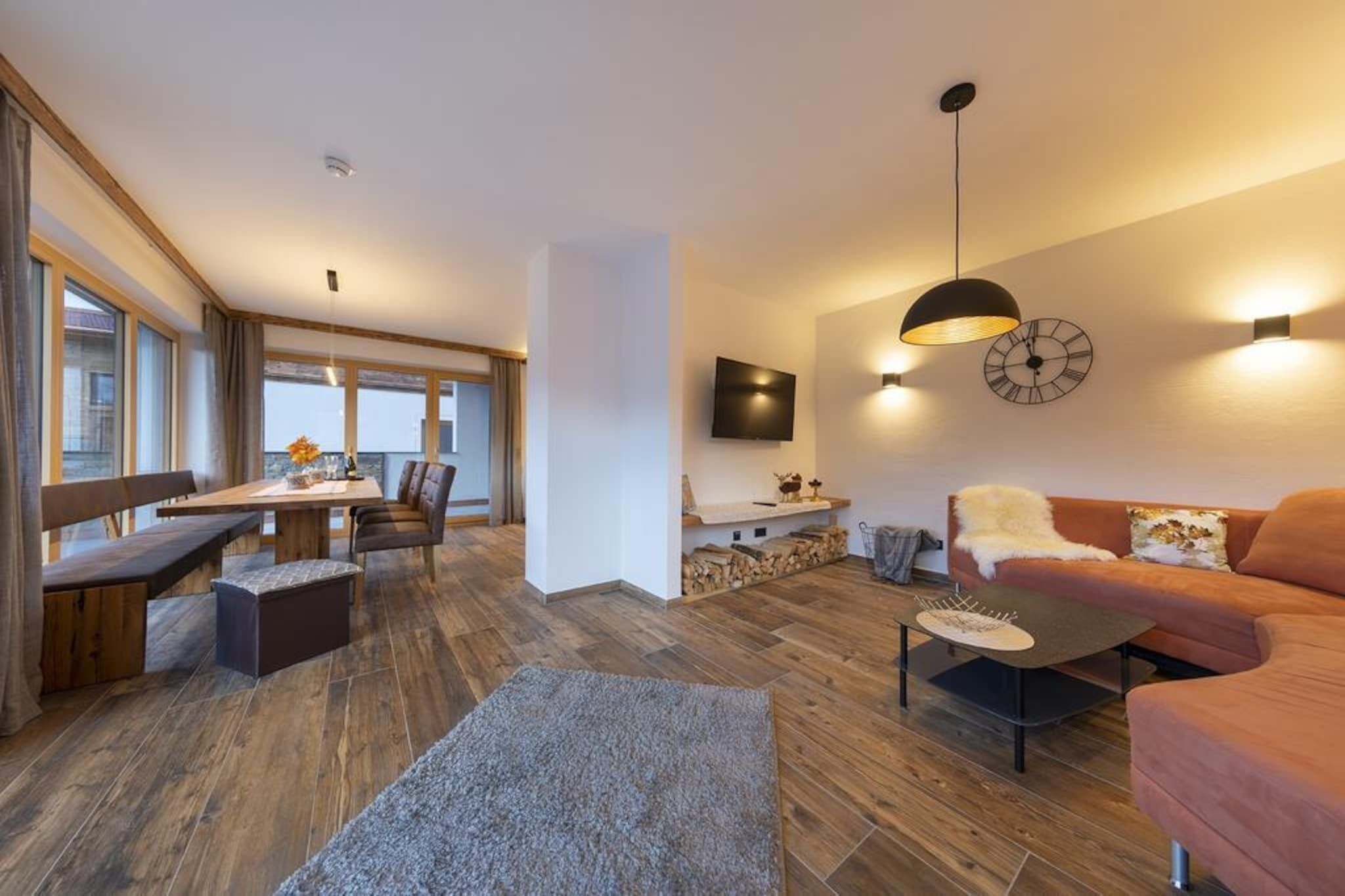 A modern living room with a sofa, a coffee table, and a TV mounted on the wall.