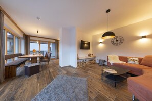 Una sala de estar moderna con un sofá, una mesa de centro y un televisor montado en la pared.