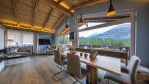 Un salon moderne avec un plafond en bois, une grande table à manger et une vue sur une montagne.