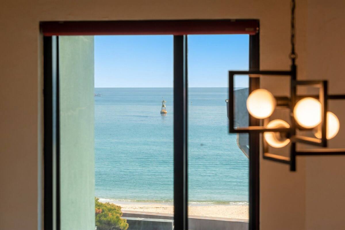A view through a window with a clear sea and a buoy in the distance.