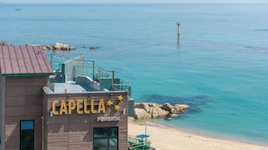 Ein KĂŒstengebĂ€ude namens 'Capella Pension' mit Blick auf das Meer und den Strand.