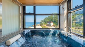 A hot tub with a view of the ocean and a house. - Capella Oceanview Spa Resort Goseong (Goseong)