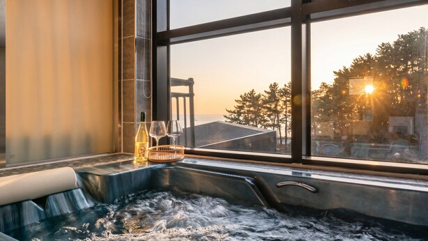 A hot tub with a view of trees and a building. - Capella Oceanview Spa Resort Goseong (Goseong)