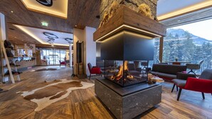 A modern interior with a stone fireplace, wooden flooring, and a view of snow-covered mountains. - Stylish Chalet by Ski Slopes (Neukirchen)