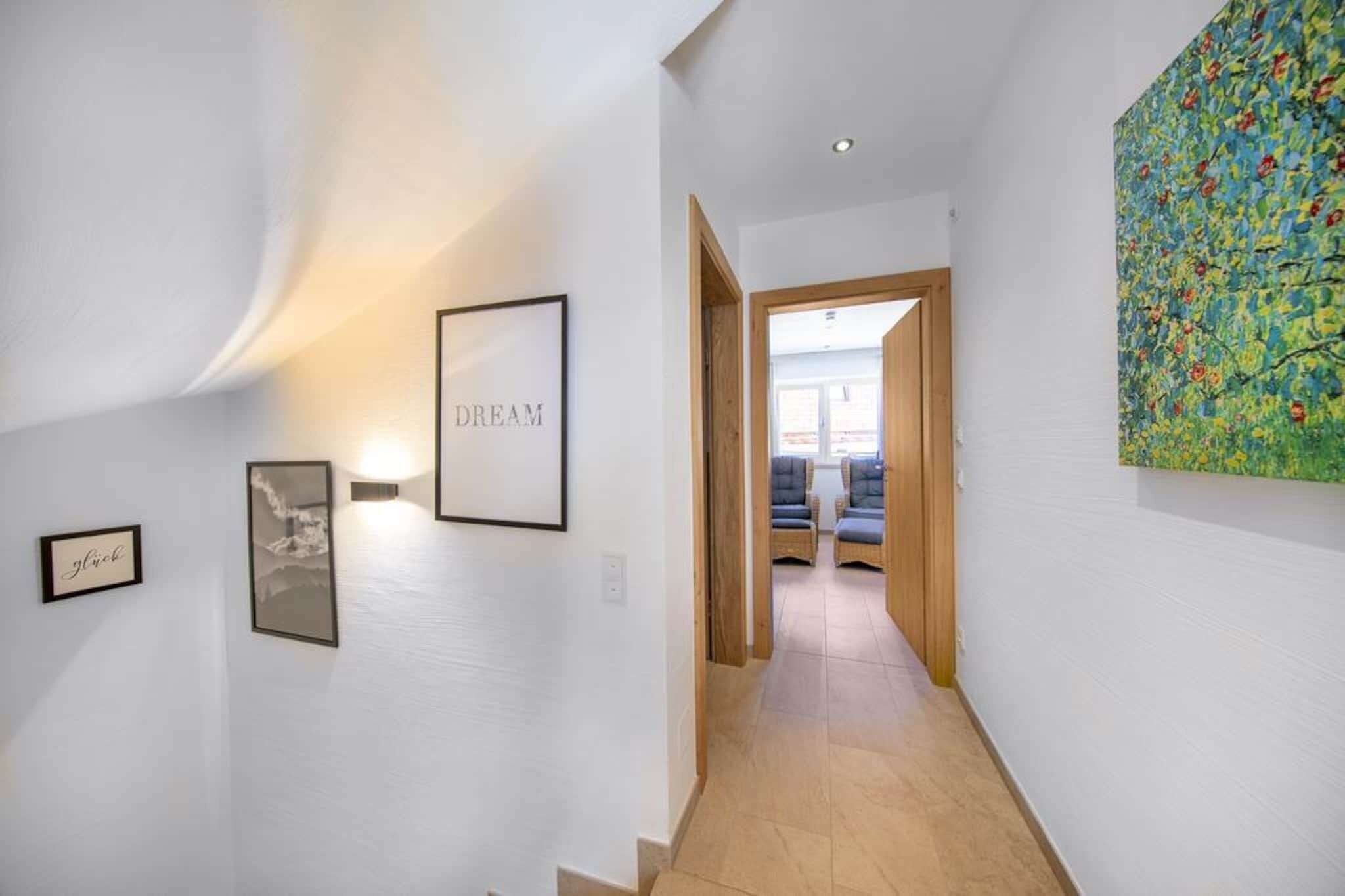 Un couloir aux murs ornés de tableaux encadrés, une porte en bois au fond, et une peinture abstraite aux couleurs vives sur le côté droit.