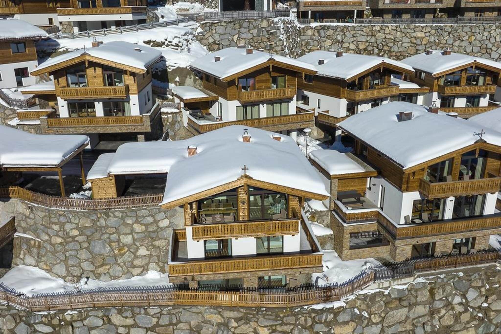 Eine Gruppe von Chalets mit Stein Fundamenten und Holz Balkonen, umgeben von Schnee.