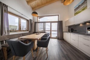 Una cocina moderna con una mesa y sillas de madera, ventanas amplias y vistas al exterior.