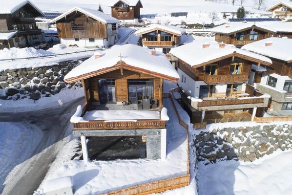 Un complejo turístico en la montaña cubierto de nieve, con edificios de madera y un camino de piedra.