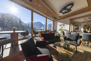 Un interior moderno con techo de madera, ventanas amplias con vistas a la montaña y una variedad de opciones de asientos.