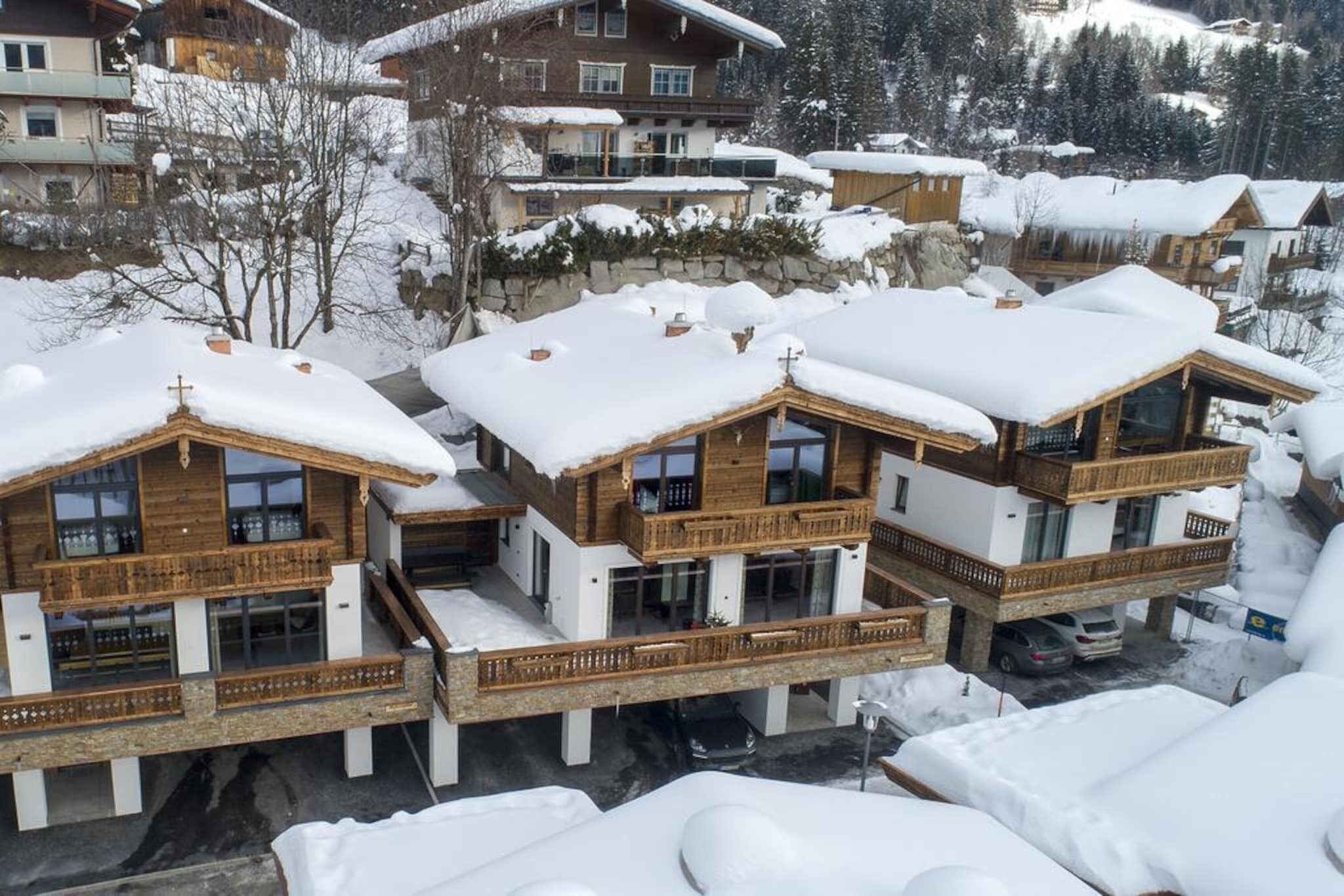 Un conjunto de edificios de estilo chalé con balcones de madera y techos cubiertos de nieve, ubicados en una zona montañosa.