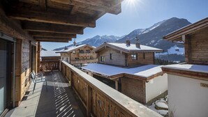 Een houten chalet met een balkon met uitzicht op besneeuwde bergen.