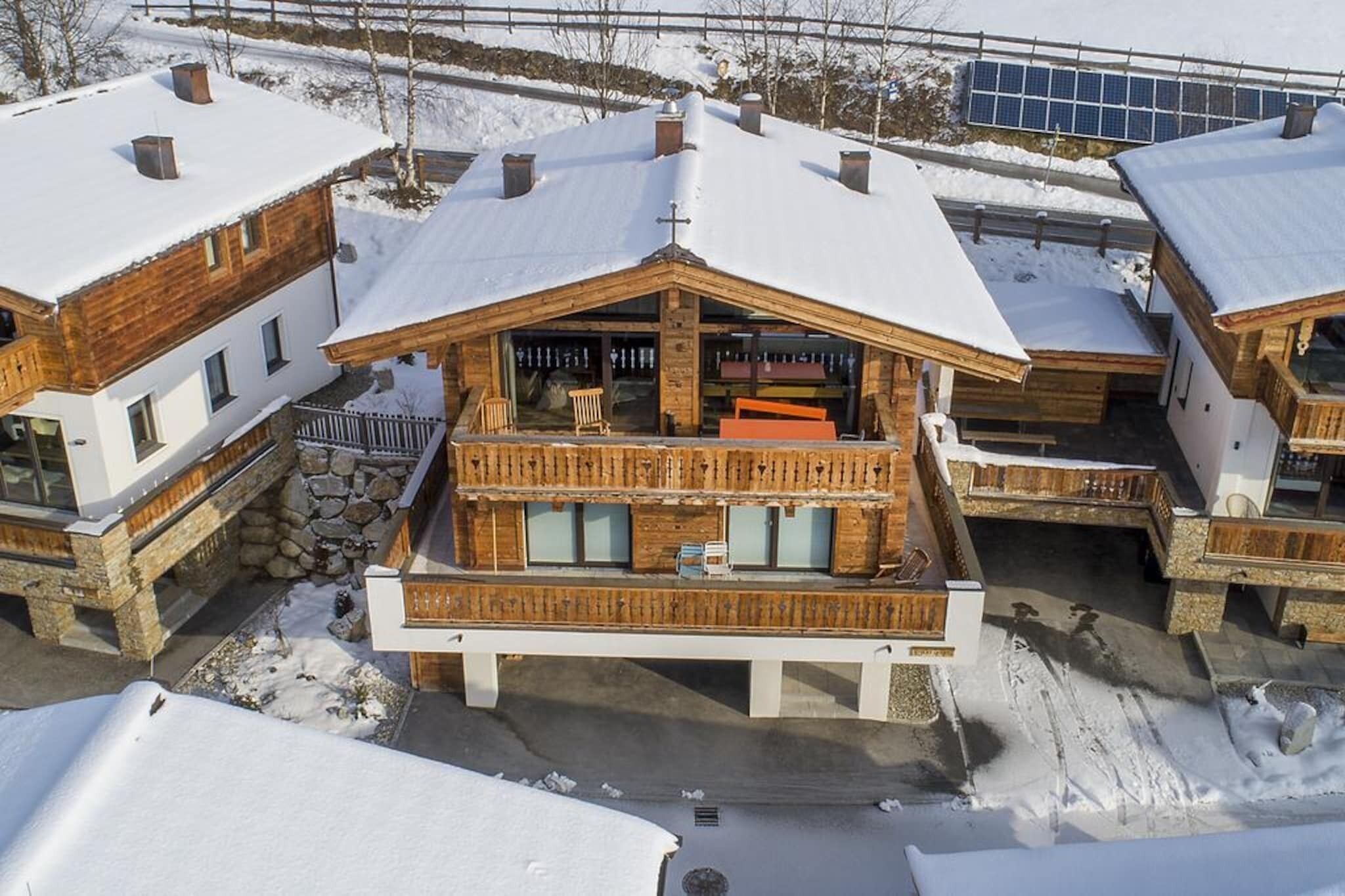 A wooden chalet with a balcony, stone foundation, and snow-covered surroundings.