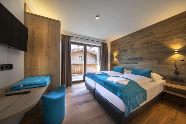 Quarto de hotel moderno com uma cama grande, uma escrivaninha e vista para um deck de madeira.