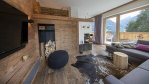 Un salon moderne avec une cheminée, un grand téléviseur, un canapé et une vue sur les montagnes.