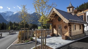 Une cabane en bois avec un toit en pente, un petit clocher et une vue sur des montagnes enneigées.