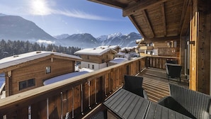 Un chalet en bois doté d’un balcon donnant sur un paysage montagneux enneigé.