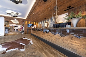 A modern reception area with a wooden ceiling, a large reception desk, and a cowhide rug on the floor.