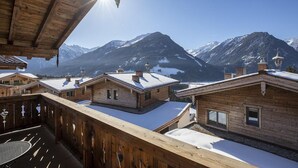 Un chalet en bois doté d’un balcon donnant sur un paysage montagneux enneigé.