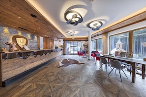 A spacious lobby with a wooden reception desk, modern lighting, and large windows offering a view of the outdoors.