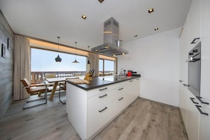 A modern kitchen with a central island, white cabinetry, and a large window providing natural light. - Chalet in Neukirchen near Ski Lift & Sauna (Neukirchen)