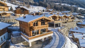 A snow-covered mountain resort with wooden cabins and a stone-walled courtyard.
