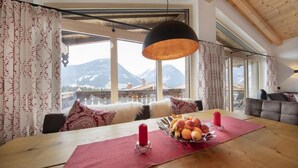 A dining area with a wooden table, red placemats, and a fruit bowl. - Wellness Chalet near Wildkogel (Neukirchen)